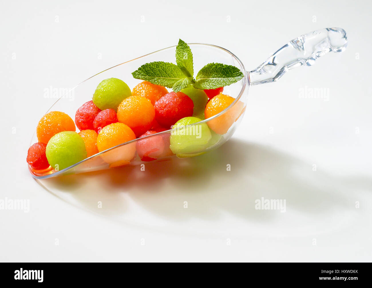 en dosificador de cristal sobre fondo blanco bolitas de melon de dos clases y de sandia Stock Photo