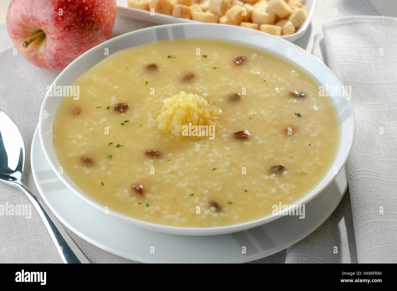en plato redondo sopa de semola de trigo con tacos de jamon y pure de manzana Stock Photo