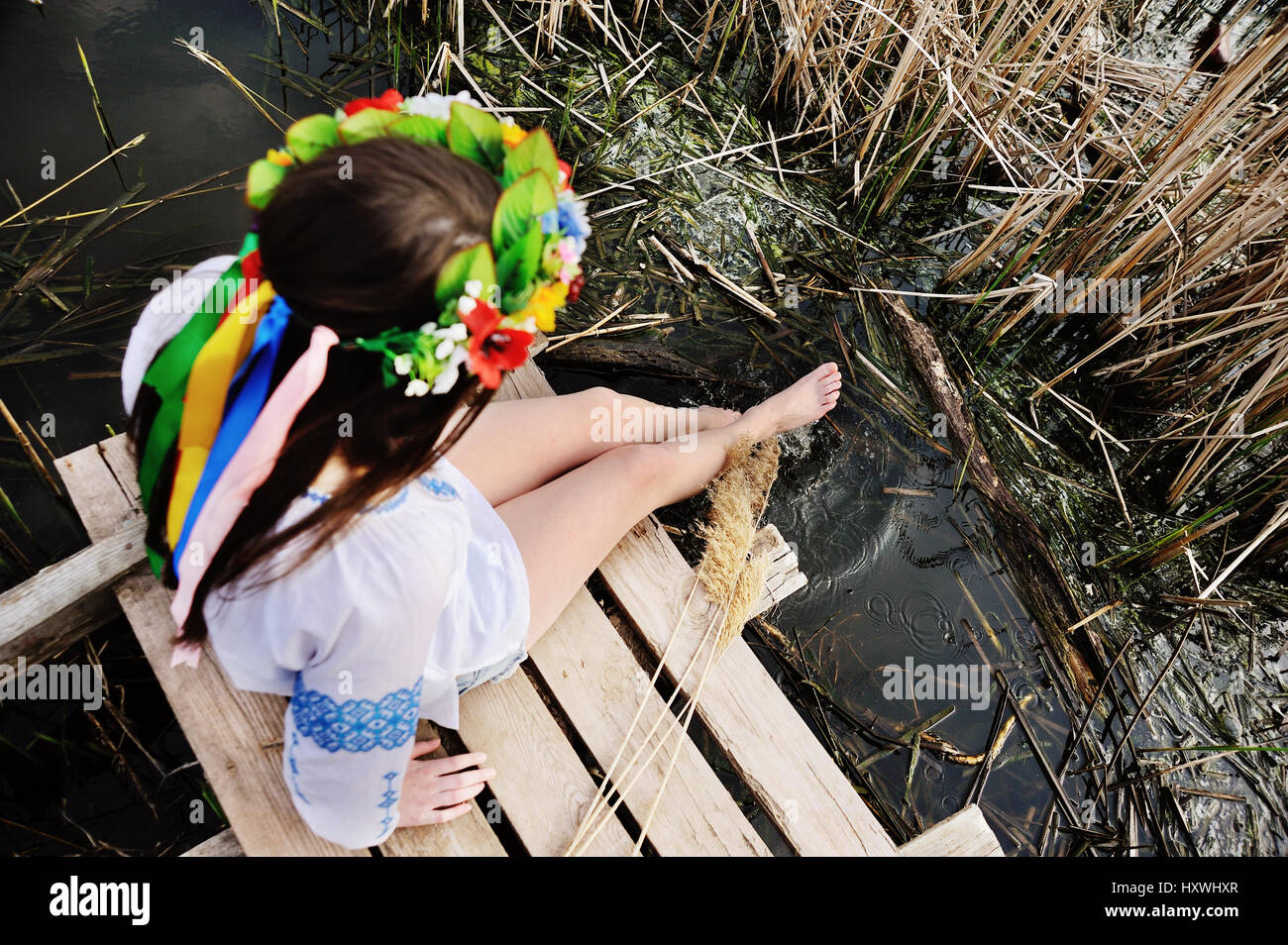 girl wets feet in the river. girl sitting on the bridge in the U Stock Photo