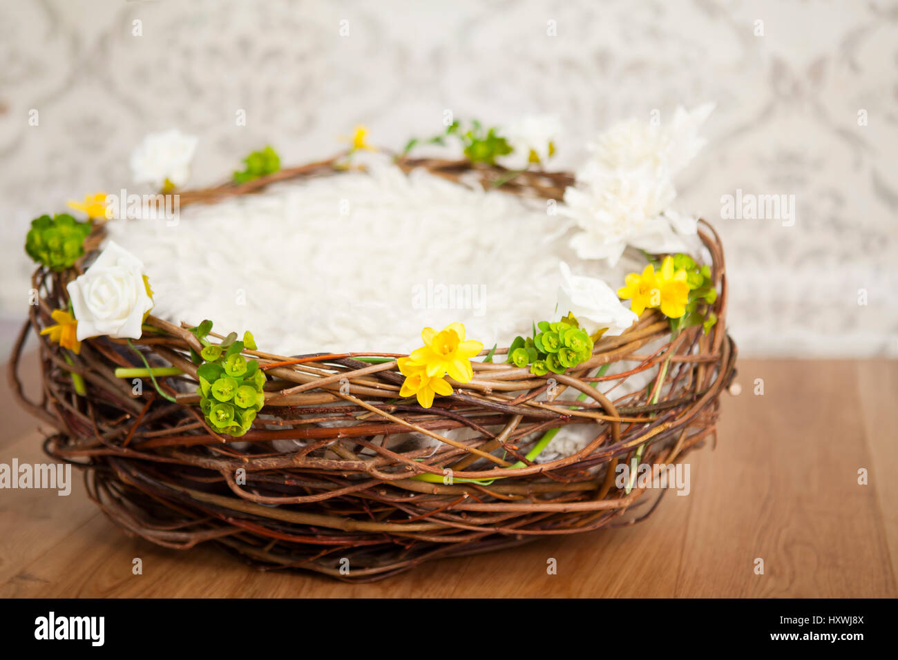 Empty basket with blanket. Easter nest, with spring flowers garland