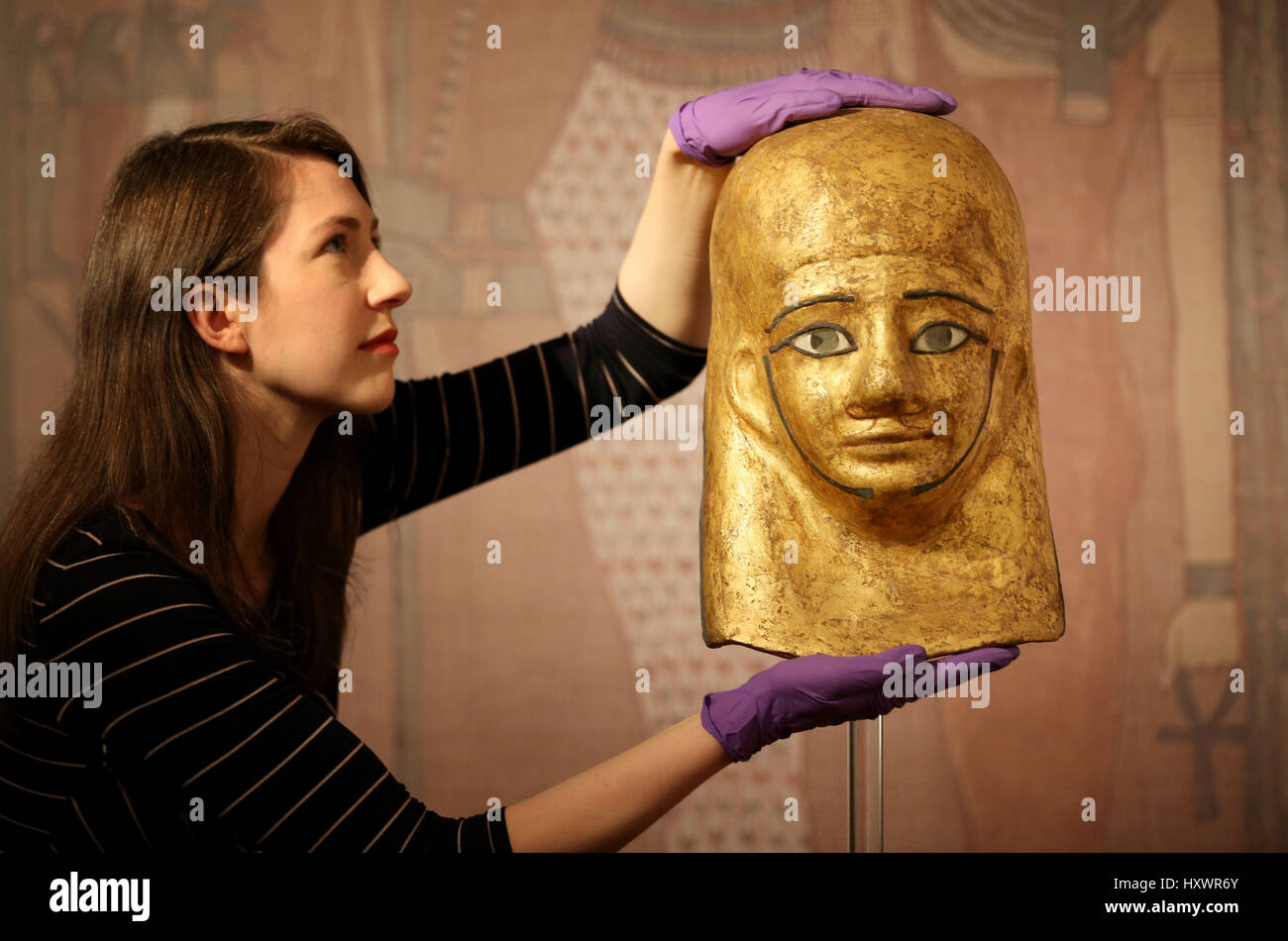 Senior curator Dr Margaret Maitland takes a closer look at the gold mummy-mask of Montsref which is on display in The Tomb: Ancient Egyptian Burial exhibition at the National Museum of Scotland in Edinburgh. Stock Photo