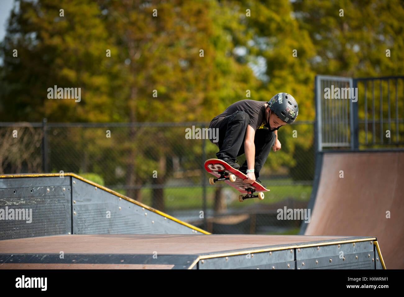 young boy skate boarding jumping high holding board Stock Photo