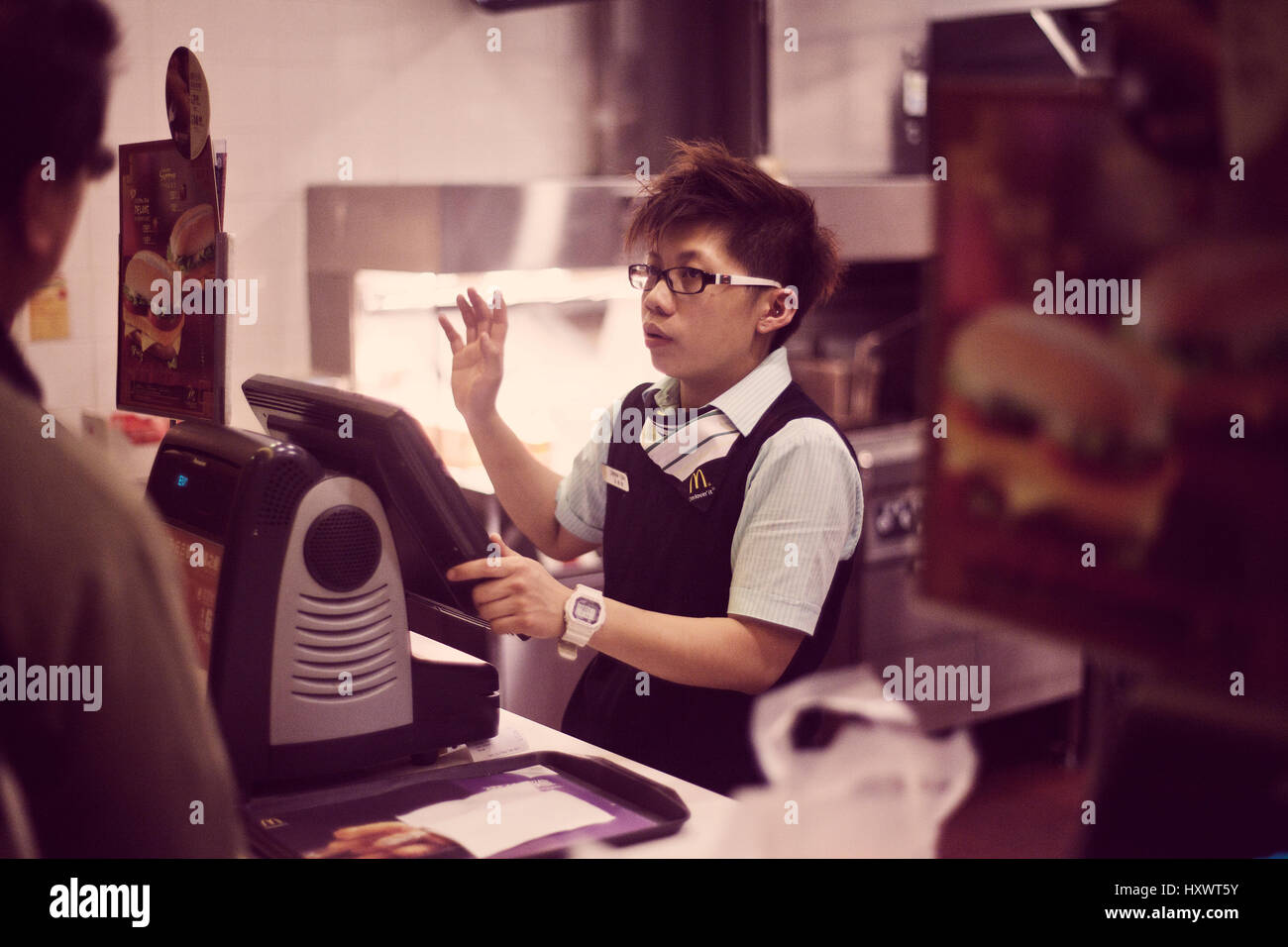 A Chinese cashier at the counter of McDonalds in Hong Kong, China. The fast food chain McDonalds is becoming more and more popular in China. Hong Kong Stock Photo