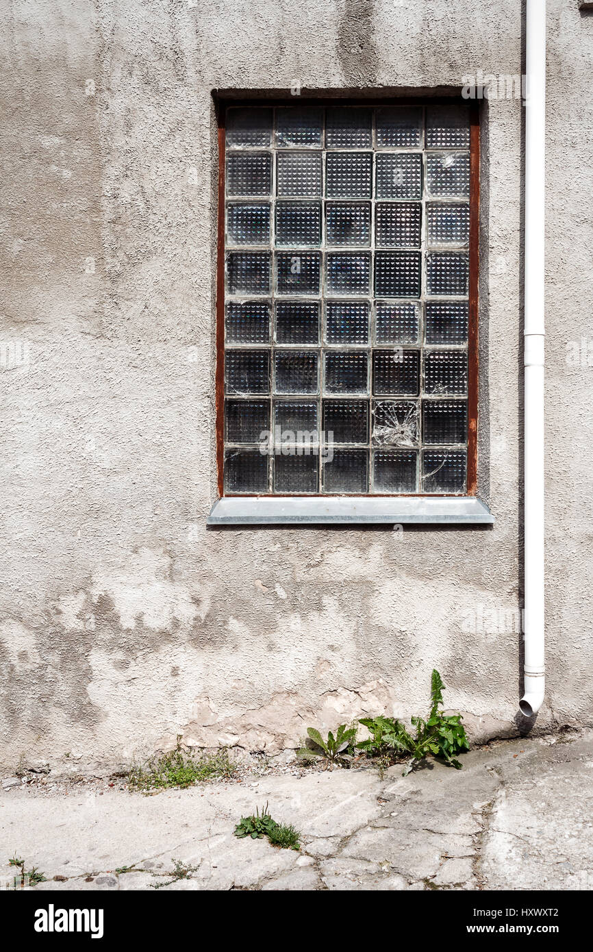 Concrete wall with glass block window and ground. Architecture