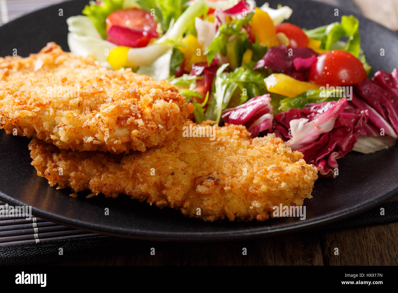 Chicken cutlets in breadcrumbs Panko and fresh salad mix macro on the plate. horizontal Stock Photo