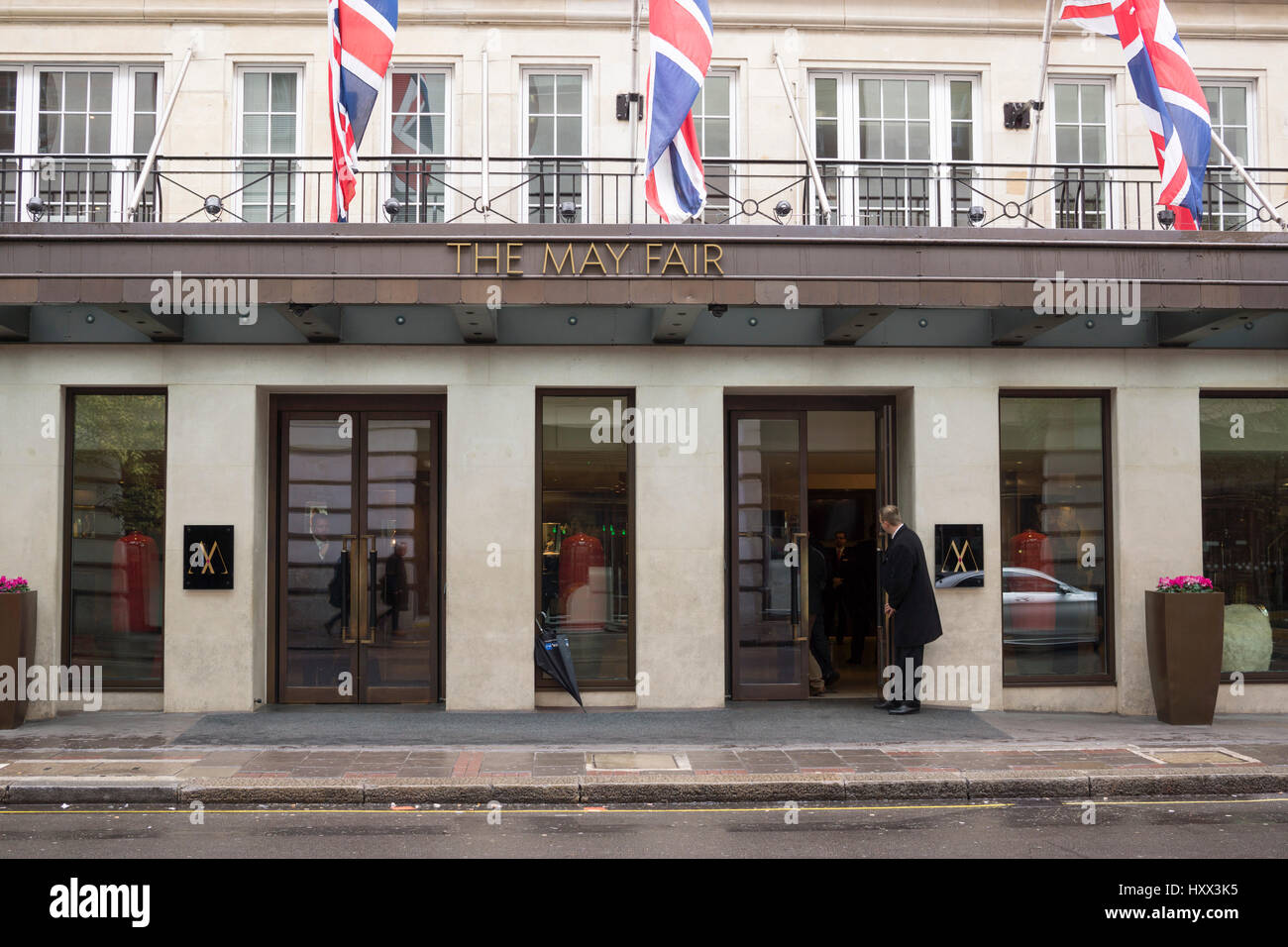 A doorman opens the door at the entrance to The May Fair Hotel on Stratton Street in London Stock Photo