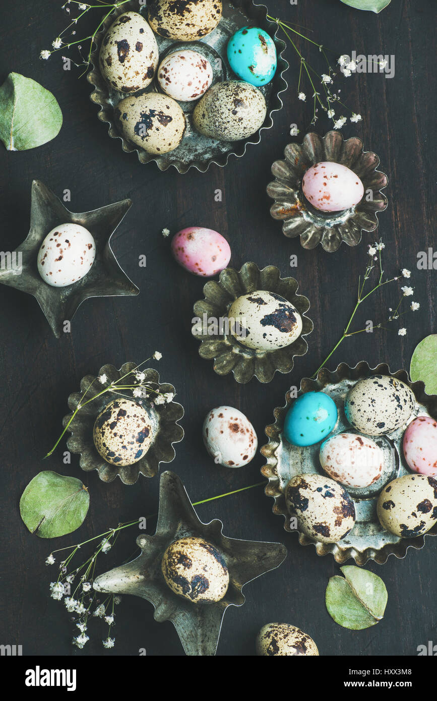Colorful painted quail eggs in metal molds, dried wild flowers and
