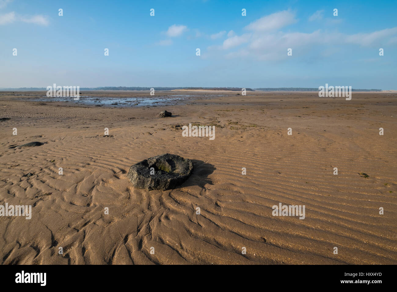 Peaceful scene at Belhaven Bay in Scotland at low tide with patterns and textures of rippled sand and an ancient round stone Stock Photo