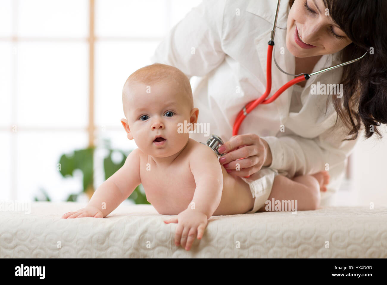 Pediatrician doctor examines baby with stethoscope checking heart beat. Stock Photo