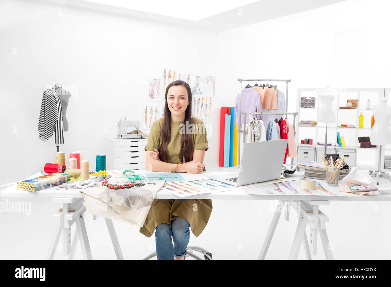 young saleswoman sitting at the desk in front of her laptop in the showroom Stock Photo