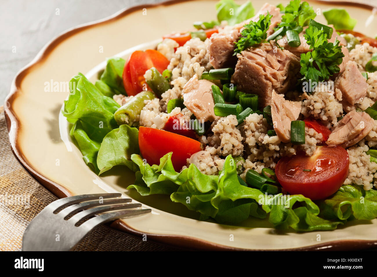 Tasty salad with couscous, tuna and vegetables on the plate Stock Photo