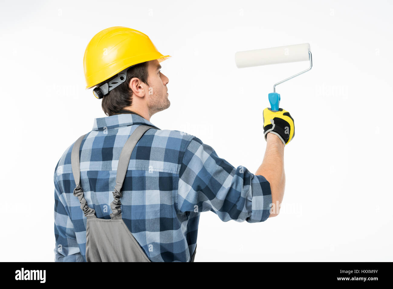 Professional workman in hard hat painting wall with paint roller Stock