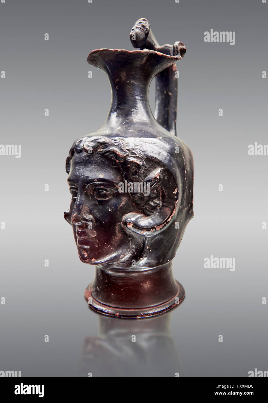 Etruscan bucchero jug with a face,  National Archaeological Museum Florence, Italy , against grey Stock Photo