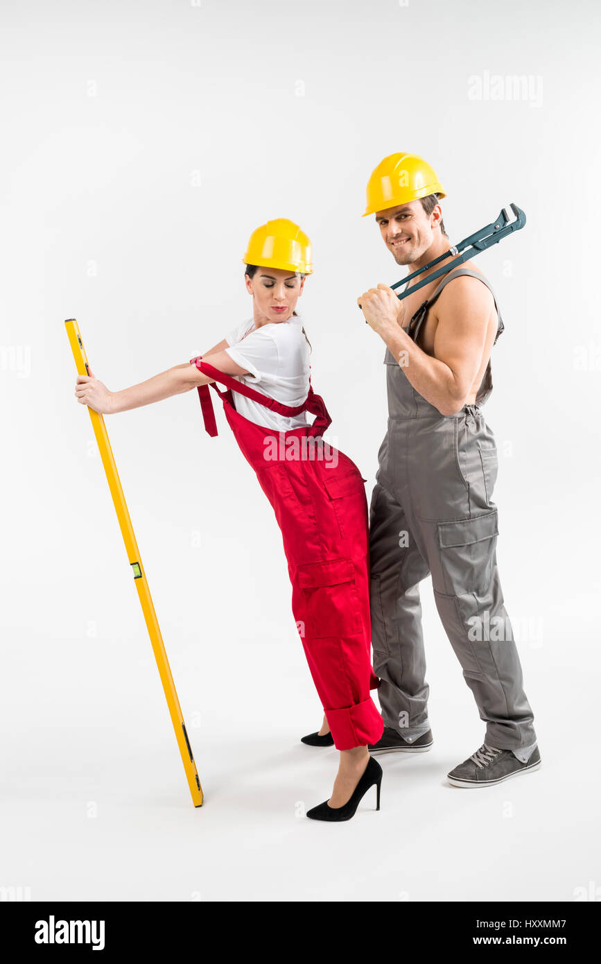 Young male and female builders posing with tools on grey Stock Photo
