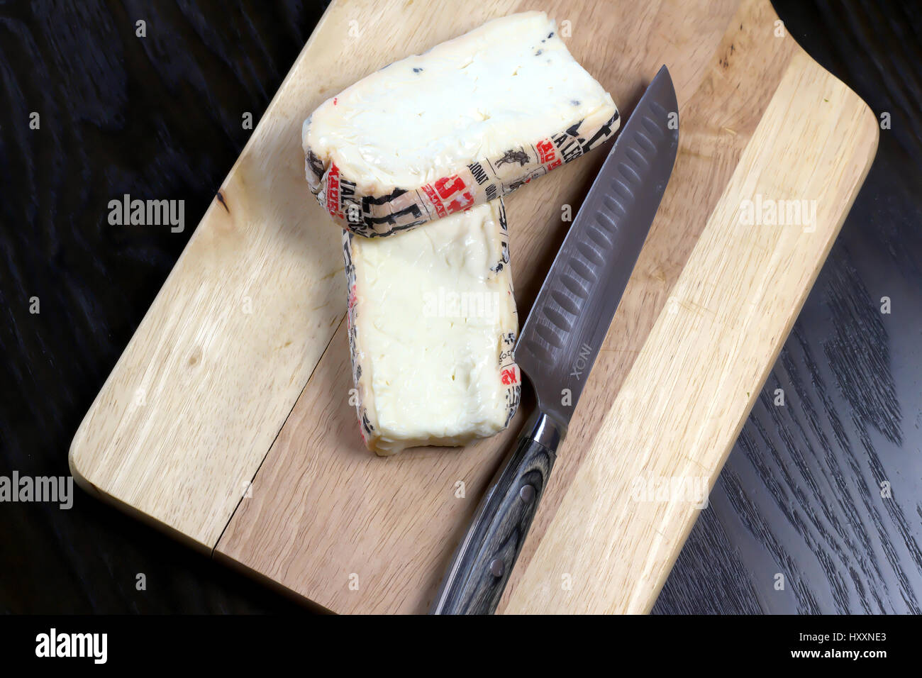 Cut Italian Taleggio Cheese on wooden cutting board with knife - Lombardy typical cheese with strong aroma, but its flavor is mild with a fruity tang Stock Photo