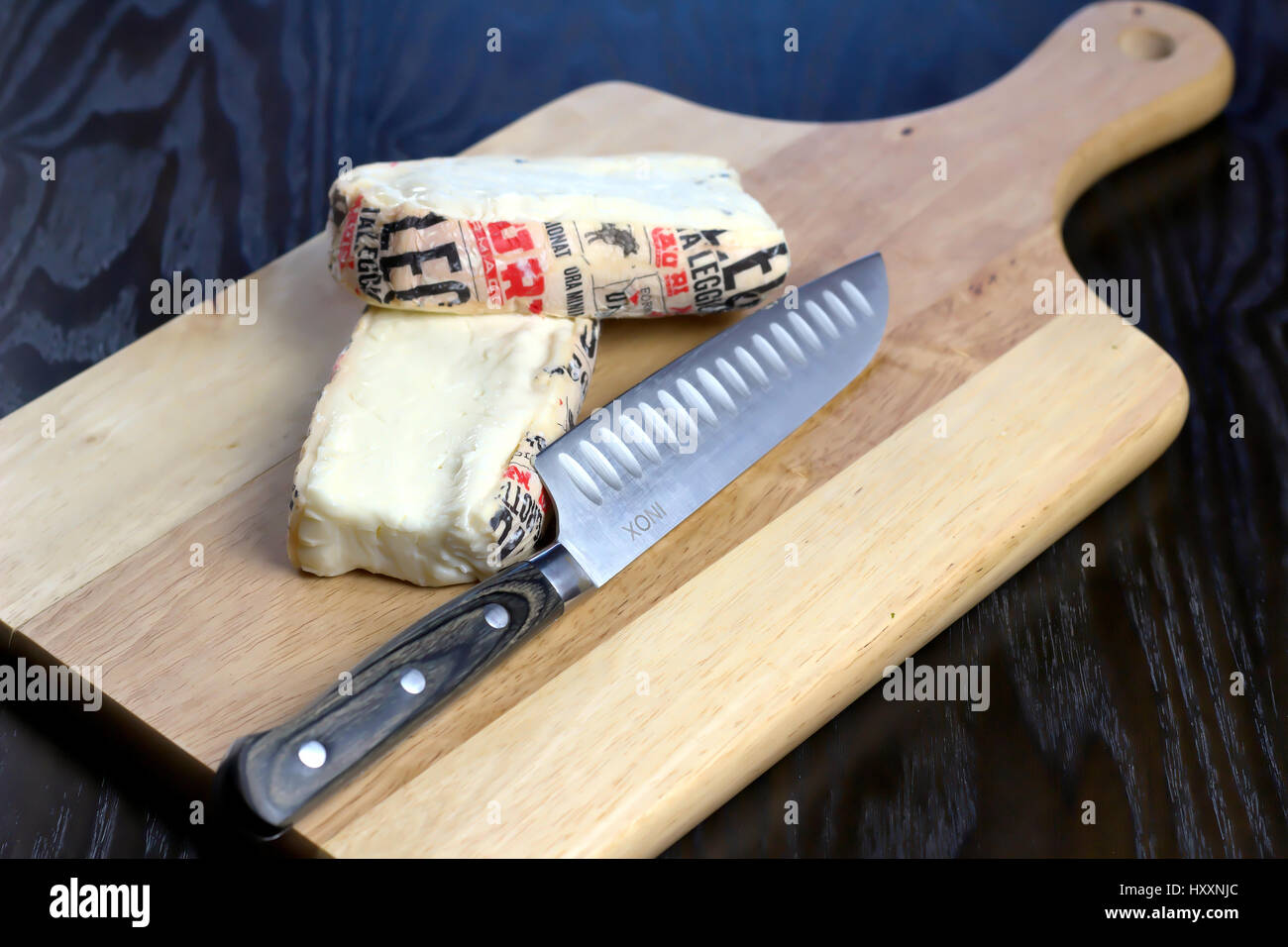 Cut Italian Taleggio Cheese on wooden cutting board with knife - Lombardy typical cheese with strong aroma, but its flavor is mild with a fruity tang Stock Photo