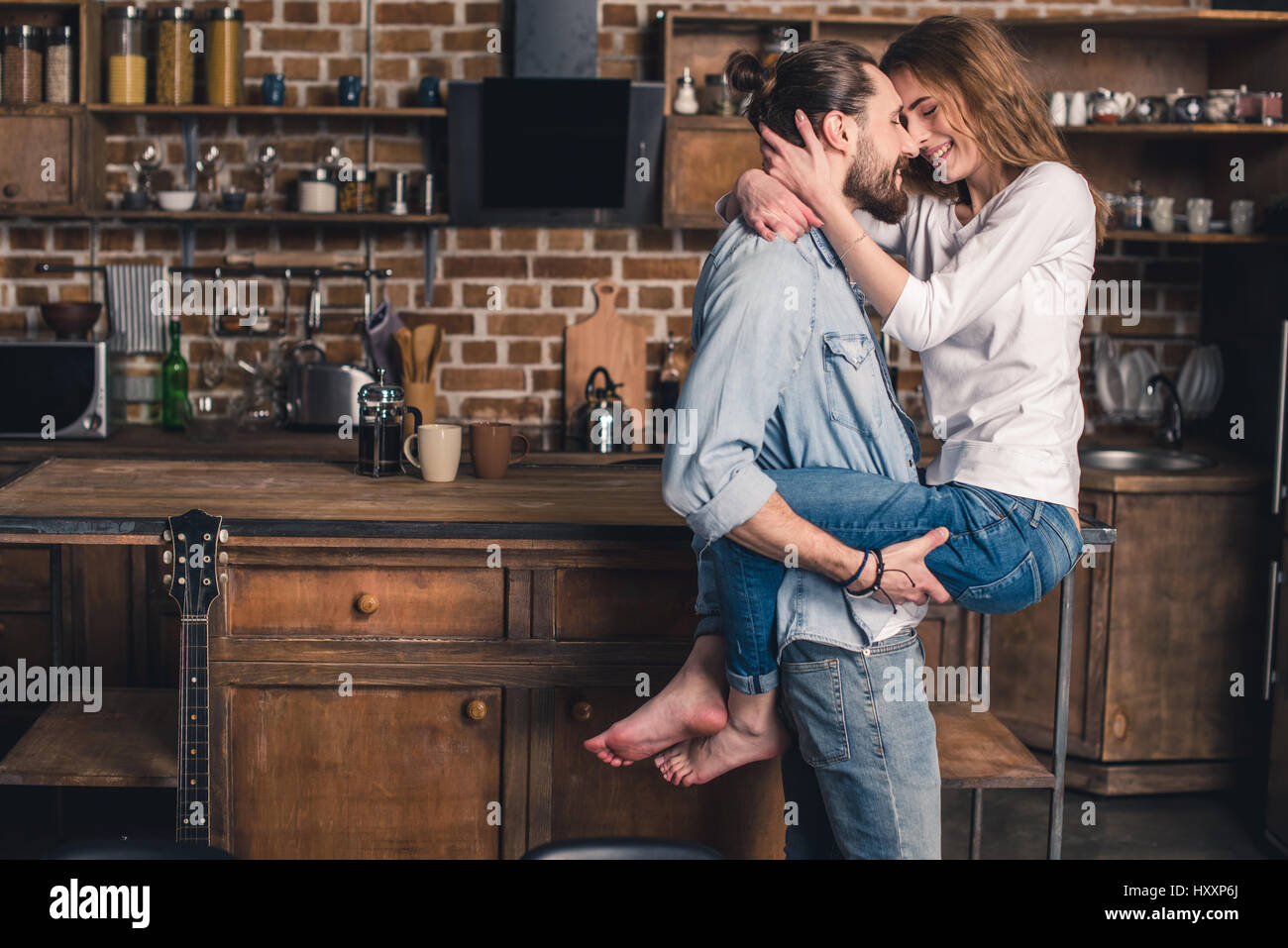 Happy young couple in love in the kitchen looking at each other Stock Photo