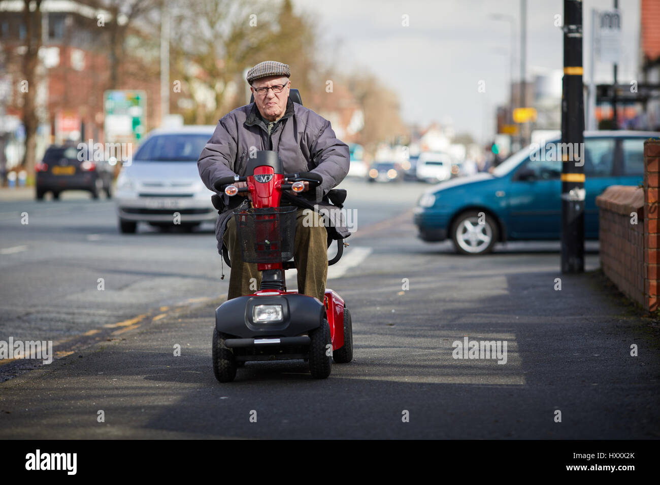 An Old aged man driving his mobility scooter along Washday Road's pavement  Sale in  Manchester, England,UK Stock Photo