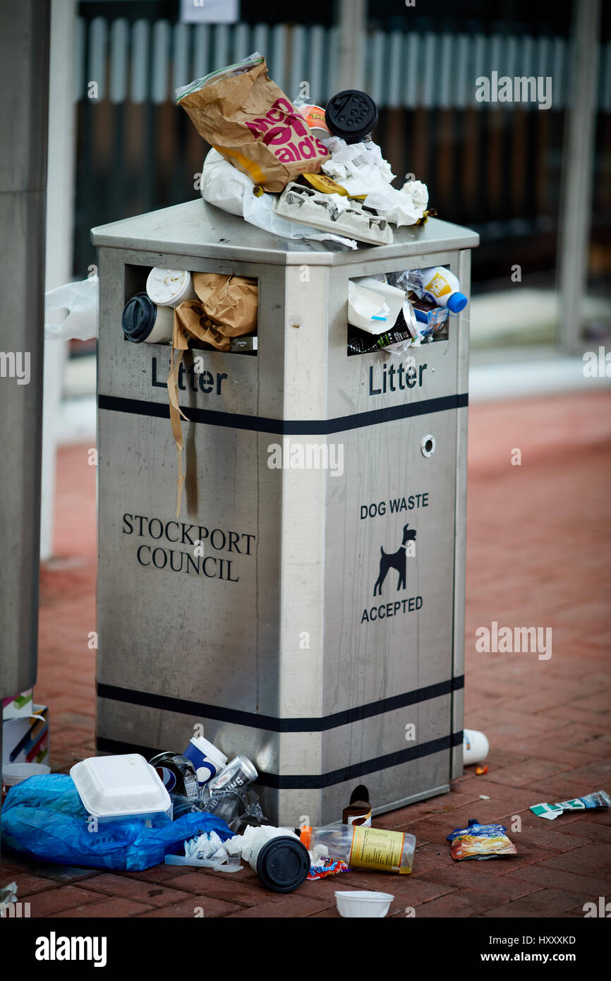 Litter bin overflowing onto the pavement and street at Stockport town