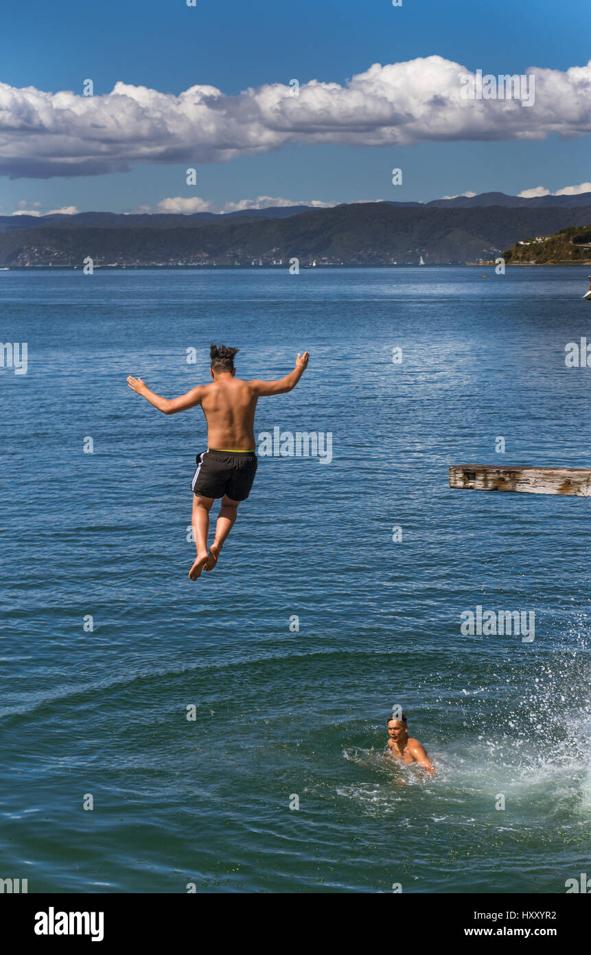 Wellington, New Zealand - February 11, 2017: Wellington waterfront with teenagers jumping off a diving board near Frank Kitts Park and lagoon bridge. Stock Photo