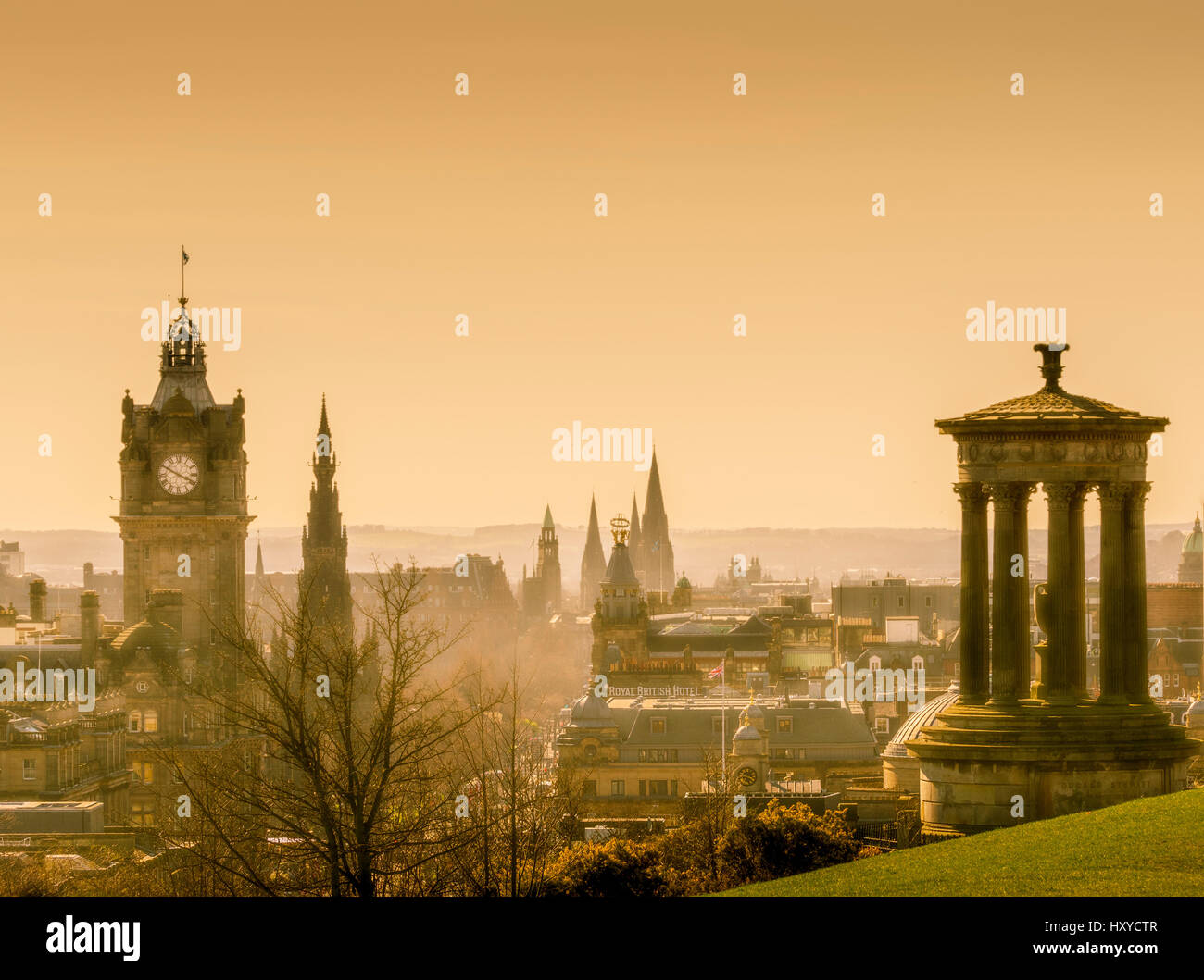 The Dugald Stewart Monument and Balmoral Hotel Clocktower with an atmospheric golden sky. Stock Photo