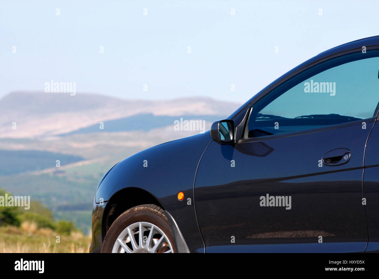 Car parked in the countryside in front of hills Stock Photo