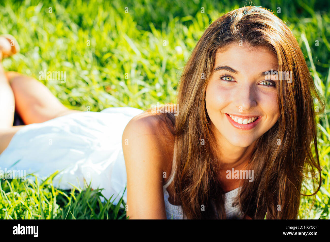 Portrait Of A Beautiful Girl Lying In The Grass In A Sunny Day Stock