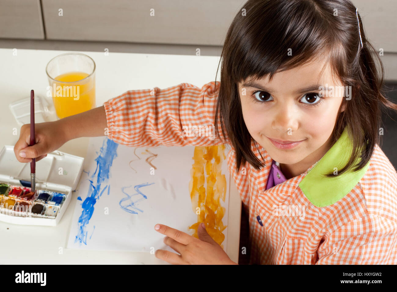 Cute little girl painting a landscape with watercolors. Looking at ...