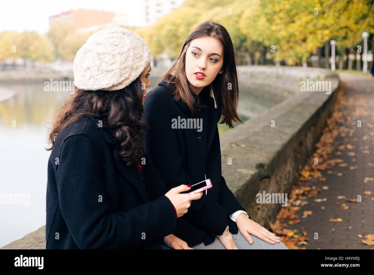 Two young beautiful women gossiping otdoors in autumn Stock Photo