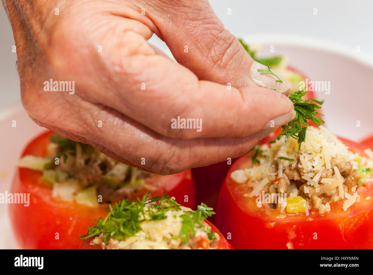 Stuffed tomatoes preparation : Adding coriander  to raw stuffed tomatoes Stock Photo