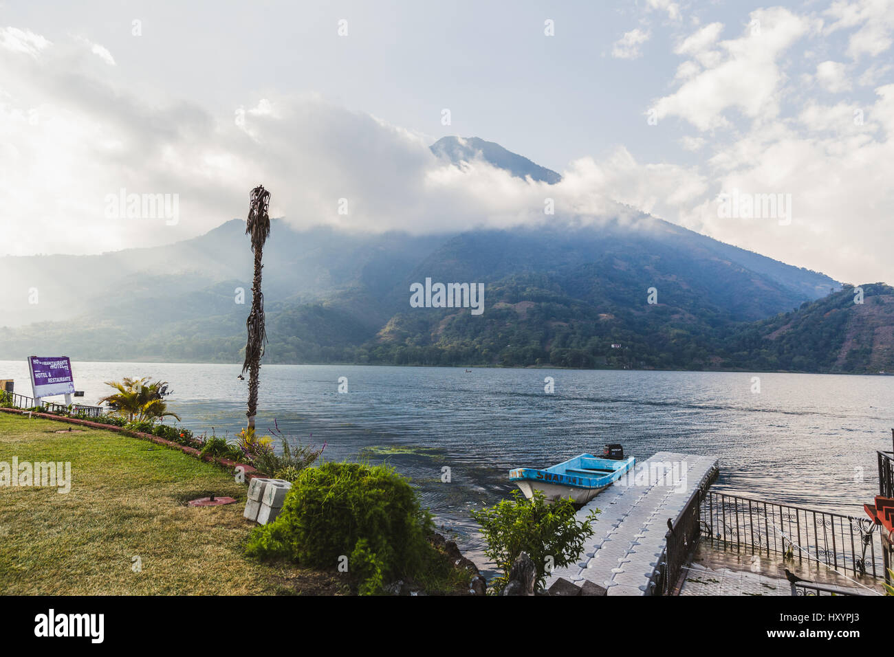Boat dock in foreground and cloud-covered volcanic mountains in the distance at Lake Atitlan, Guatemala, Central America. Stock Photo