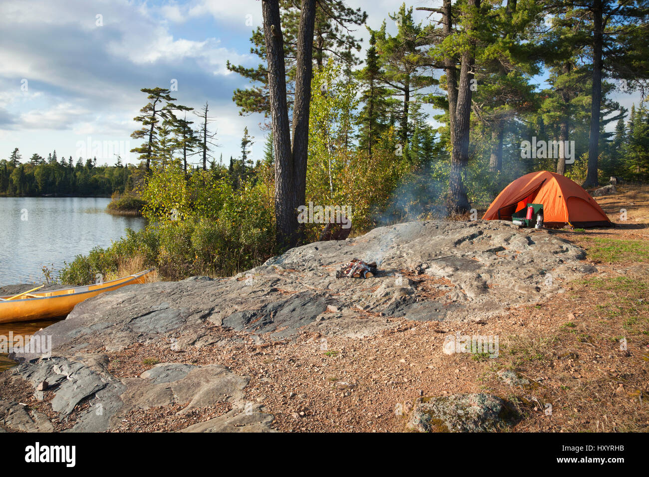 Campsite with orange tent and canoe on a lake in the Boundary Waters Canoe Area Wilderness of Minnesota Stock Photo