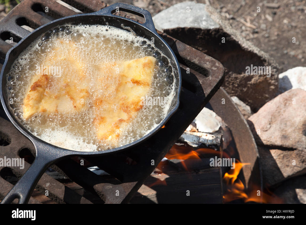 Shore lunch of frying fish in a cast iron pan on an outdoor grill Stock
