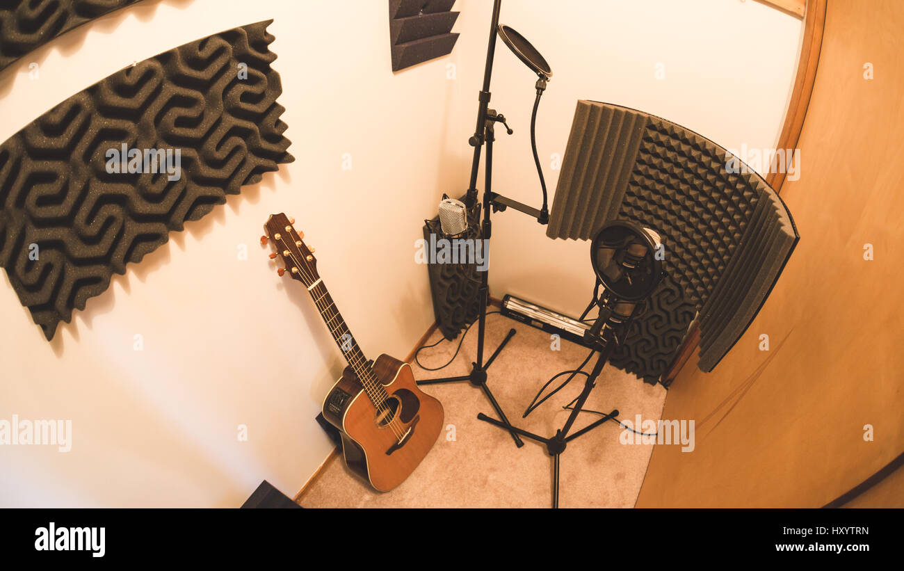 Guitar, microphones, and audio treatment panels in a recording studio room. Stock Photo