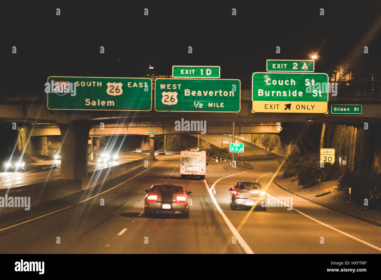 Cars driving down freeway in Portland, Oregon. Signs for Salem, Beaverton, Couch Street, and Burnside Street above. Stock Photo