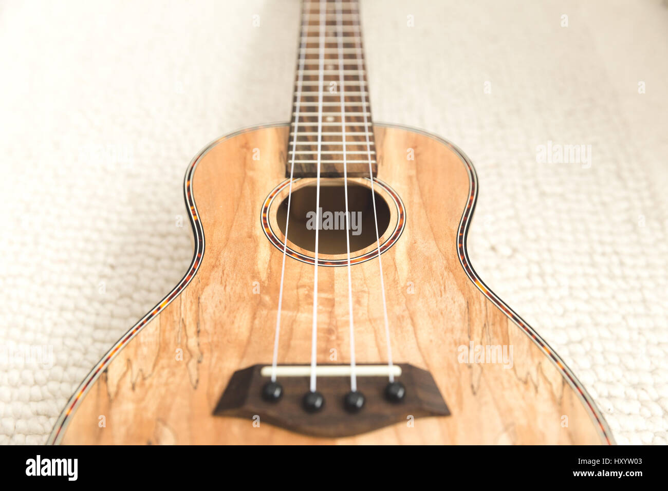 New, upscale ukulele with four strings and unique, textured wood grain finish. Stock Photo