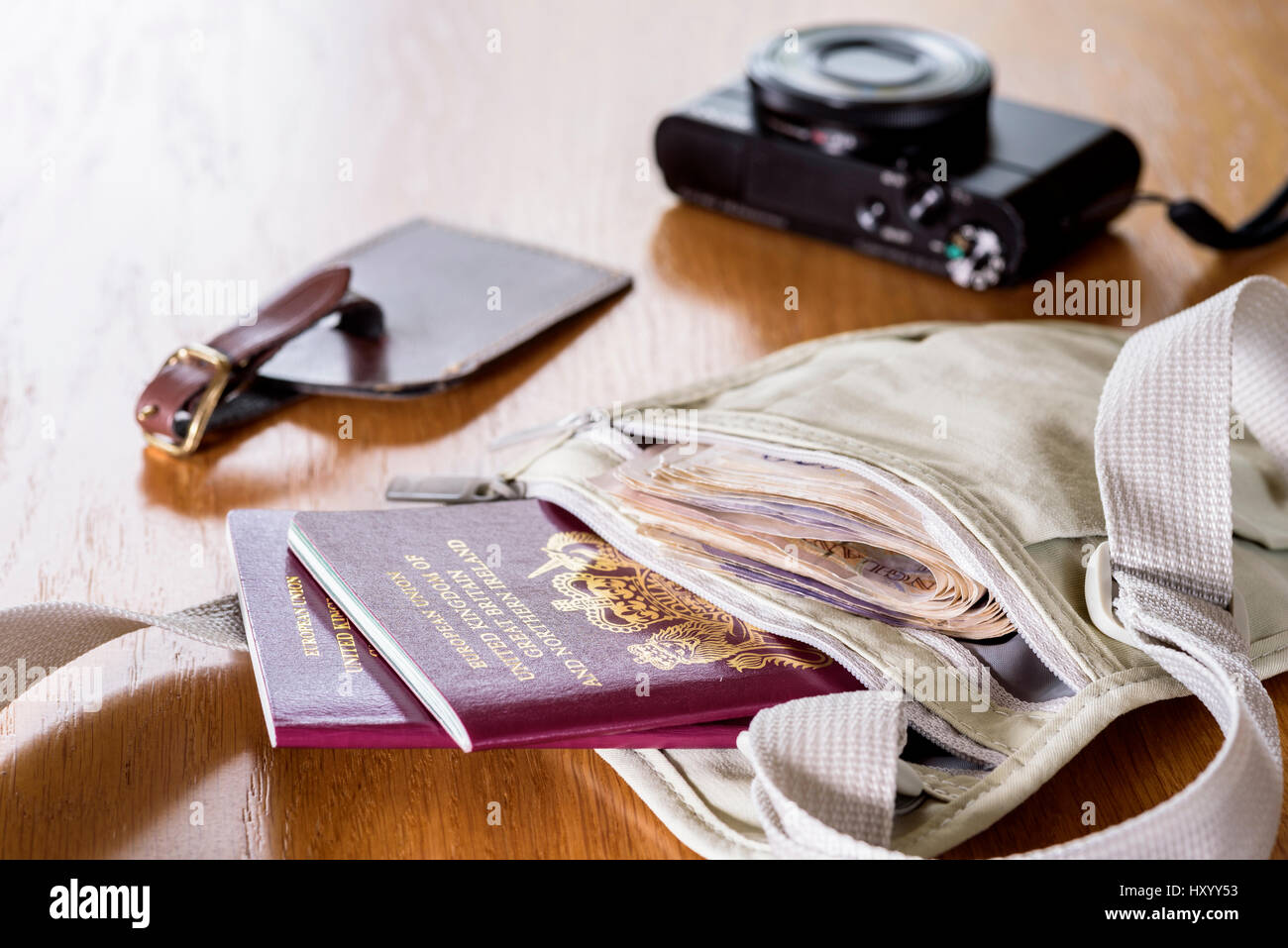 Money belt laid out on a table, with currency,  passports, camera and luggage tag. Stock Photo