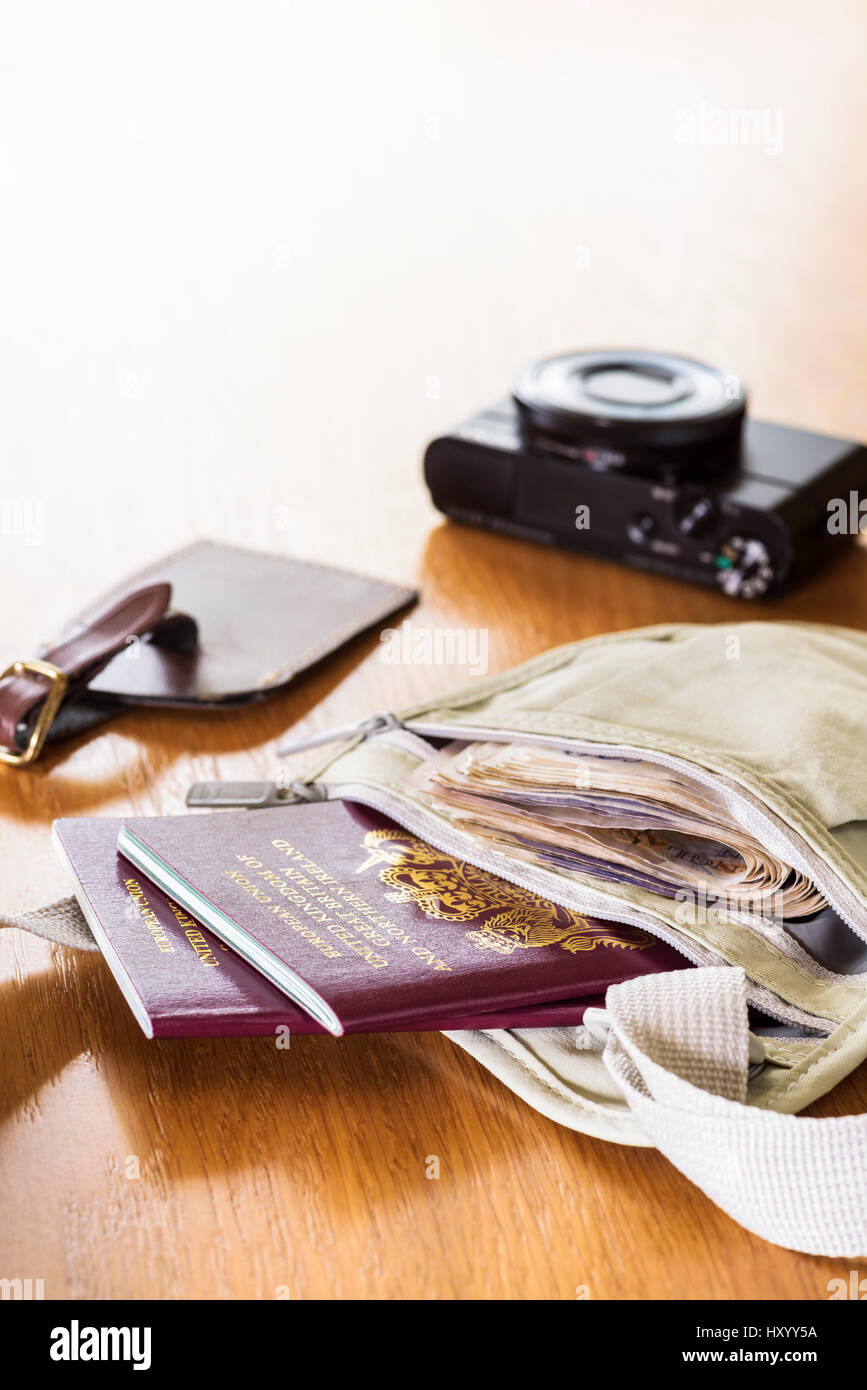 Money belt laid out on a table, with currency,  passports, camera and luggage tag. Stock Photo