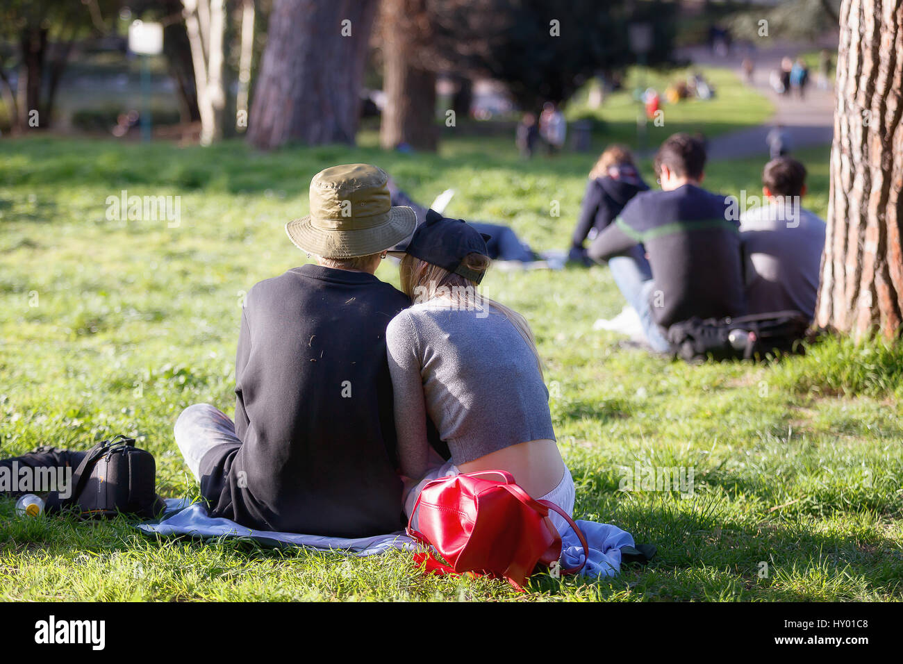 Rome, Italy - February 26, 2017: A pair of young lovers sitting on the green lawn of the Villa Borghese park on a spring day. Stock Photo