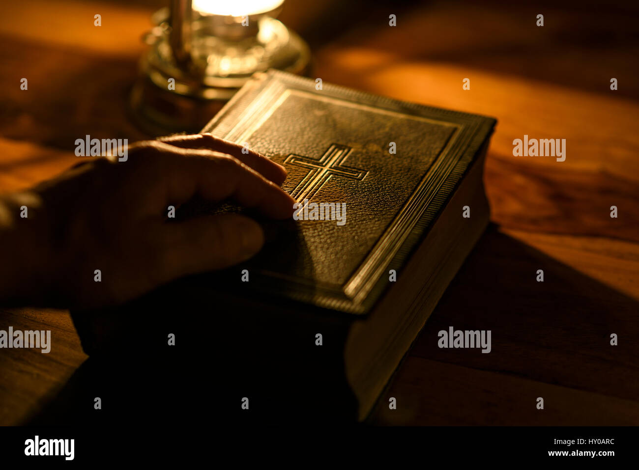 Hand on the Bible. Bible in the light of an oil lamp Stock Photo Alamy
