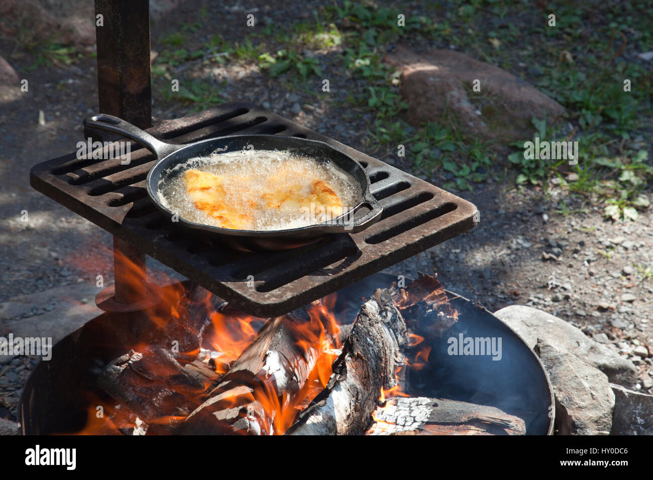 Shore lunch of frying fish in a cast iron pan on an outdoor grill Stock
