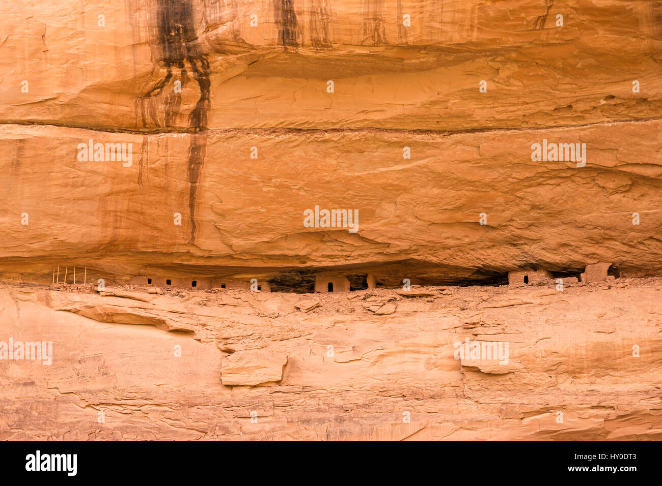 A narrow cave in a cliff wall gives shelter to ancient pueblo dwellings ...