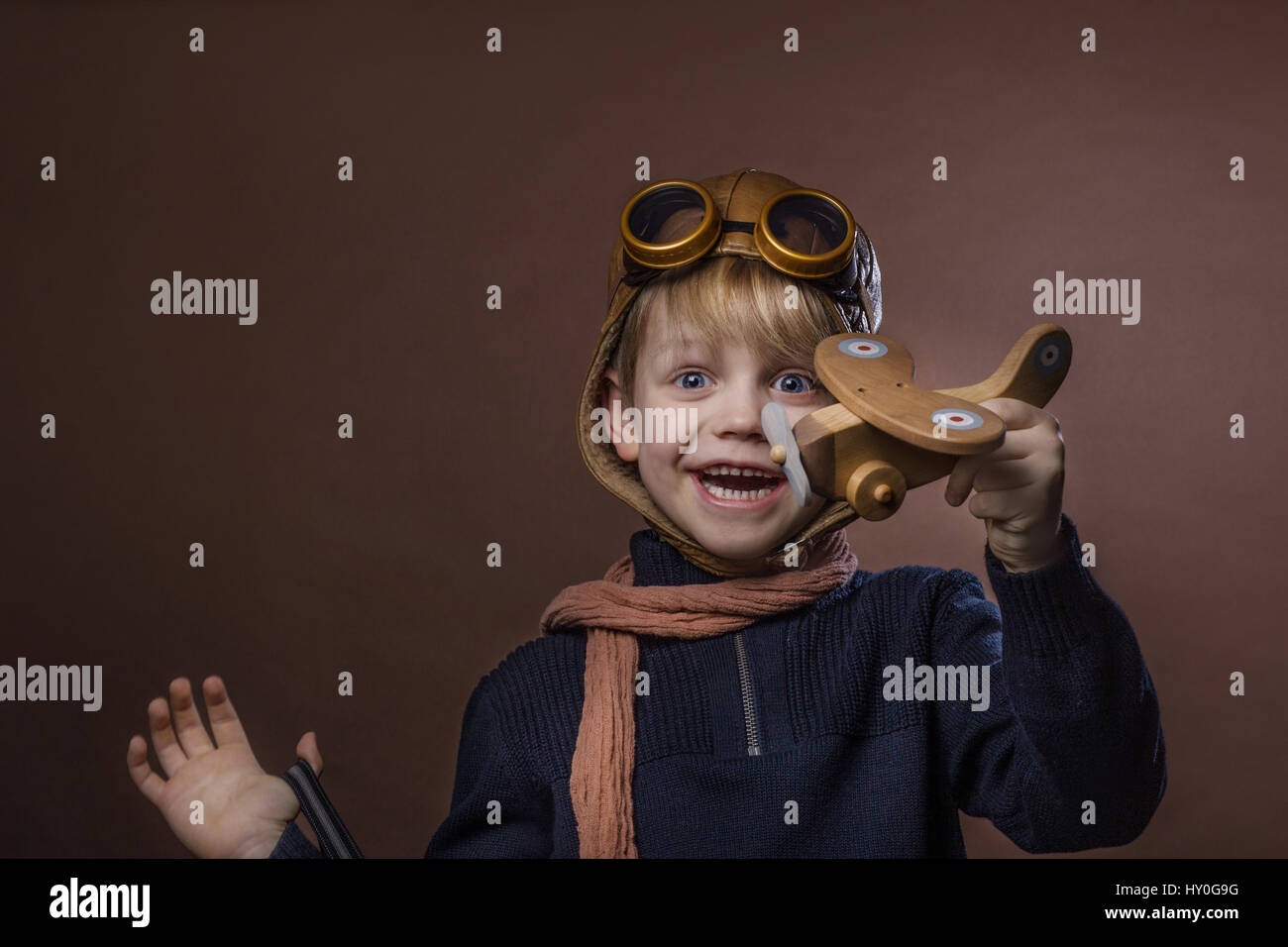 Happy child dressed in pilot hat and glasses. Kid playing with wooden ...