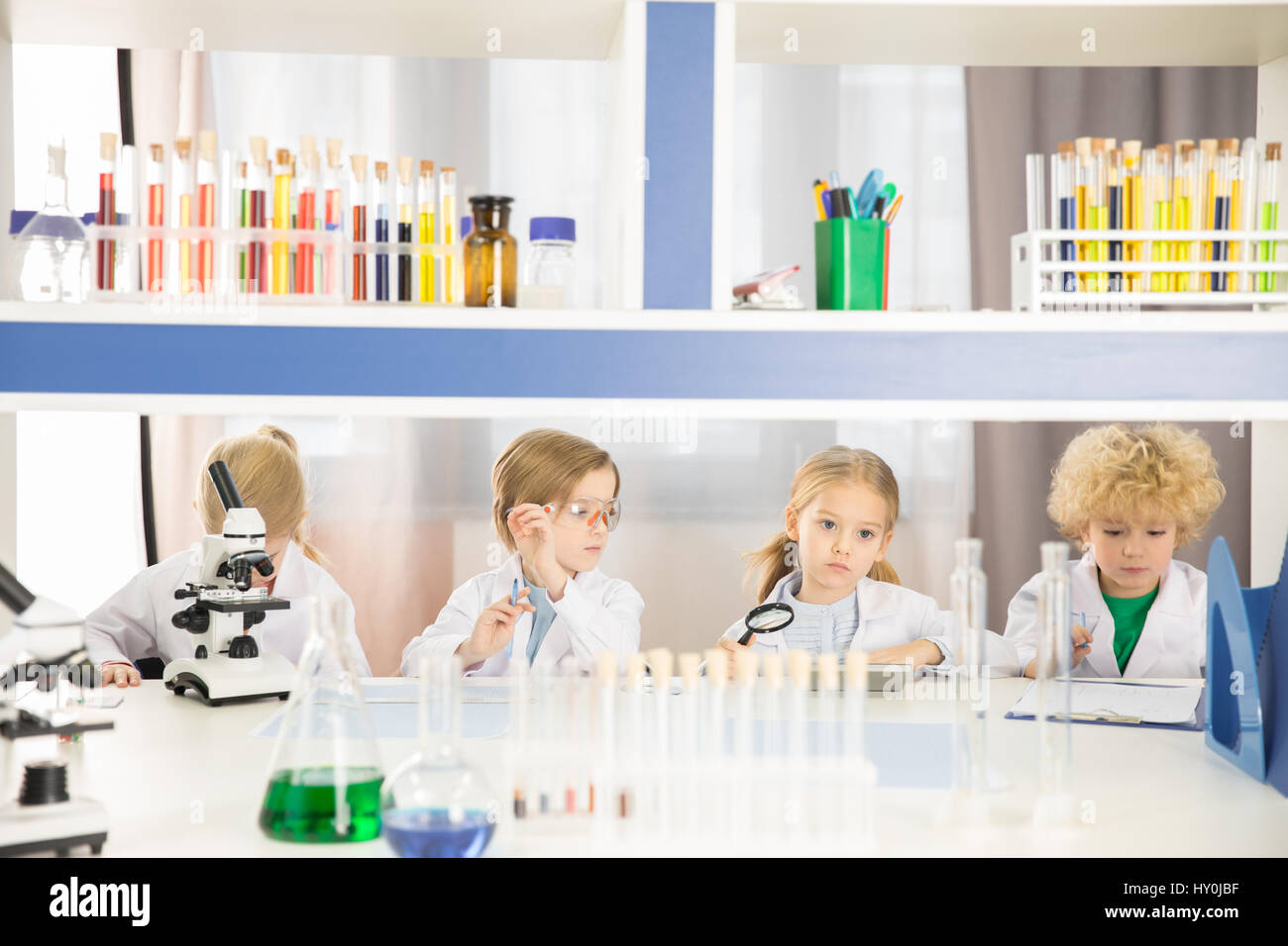 Schoolchildren in lab coats studying together in chemical laboratory Stock Photo
