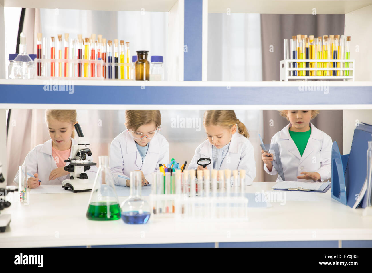 Schoolchildren in lab coats studying together in chemical laboratory Stock Photo