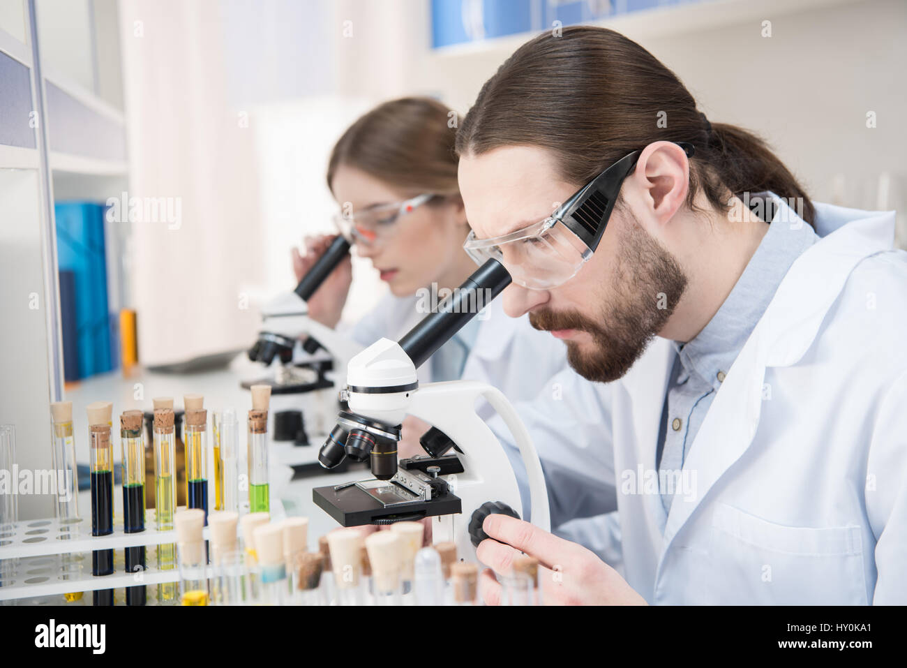 Young male and female scientists working with microscopes in laboratory Stock Photo