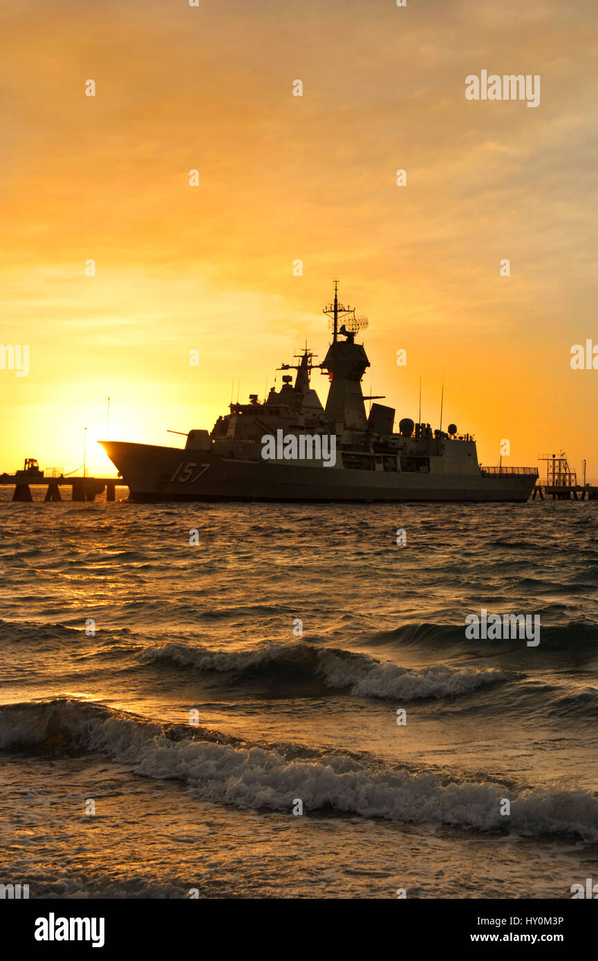 Dawn light silhouettes the Royal Australian Navy frigate HMAS Perth, at Ammunition Wharf, Garden Island naval base, Western Australia. Stock Photo