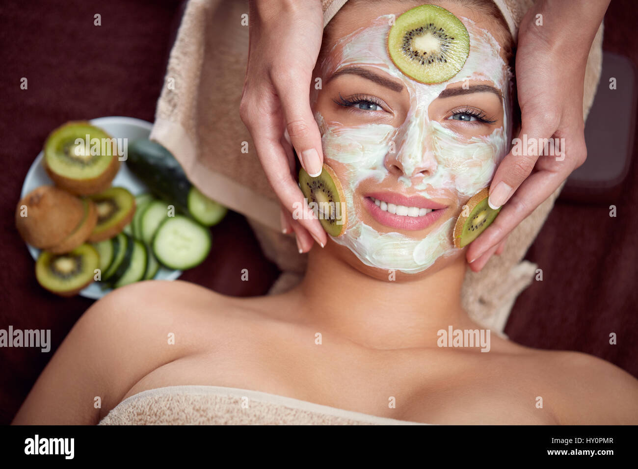 Natural cosmetic mask with cucumber and kiwi on face of smiling girl ...