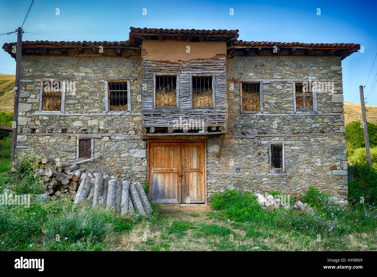 abandoned stone house with firewood next to the front door filled with straw Stock Photo