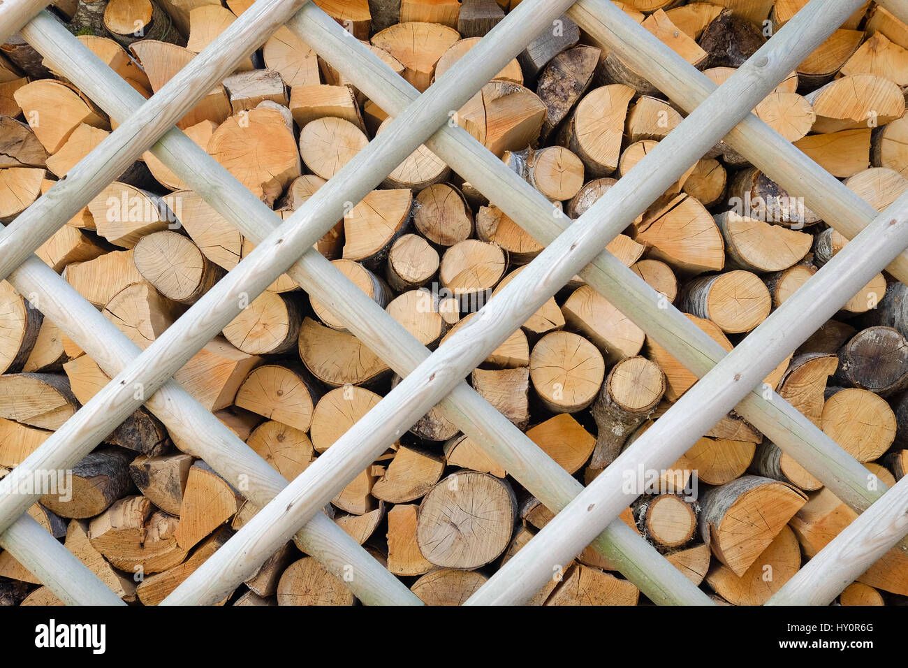 background of a pile of firewood neatly stacked behind a wooden fence Stock Photo